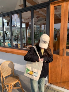 Close-up of off-white canvas tote bag with green floral print and black lettering detail