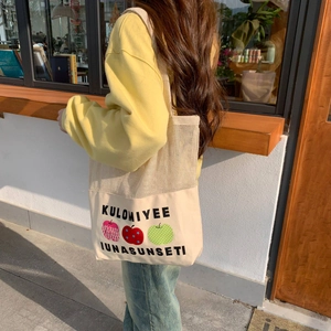 Mesh canvas tote bag with apple prints and shoulder strap shown in a daily use setting