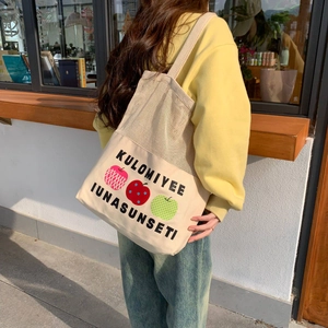 Detail of canvas mesh tote bag featuring artistic apple prints and letter patterns