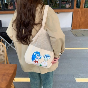 Close-up of beige mesh patchwork canvas tote bag featuring cute cartoon rabbit prints