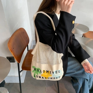 Detail of canvas mesh tote bag with palm tree print shown on model's shoulder