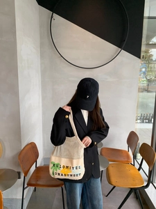 Detail of beige mesh patchwork tote bag with cartoon print and large canvas base