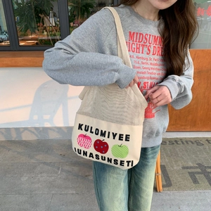 Detail of a mesh patchwork tote bag with apple print and canvas base on a model's shoulder