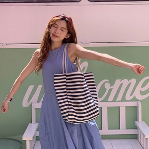 Large striped canvas tote bag with red embroidery shown in an outdoor lifestyle setting