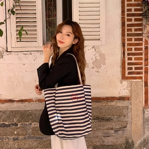 Close-up of navy striped canvas tote featuring red cat embroidery and Hello script
