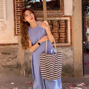 Detail of striped canvas tote bag with embroidery paired with a light blue summer dress