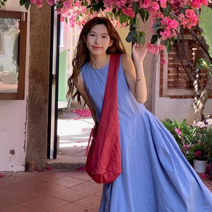 Detail of burgundy crossbody tote paired with a light blue striped summer maxi dress