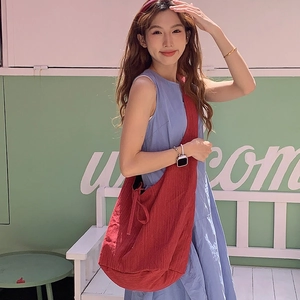 Red denim crossbody bag with pleated texture and side drawstring bow detail on shoulder