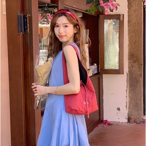 Detailed view of red textured vertical stripe tote bag with side ties against a floral cafe background