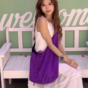 Close-up of a purple pleated vertical texture crossbody bag shown on a model