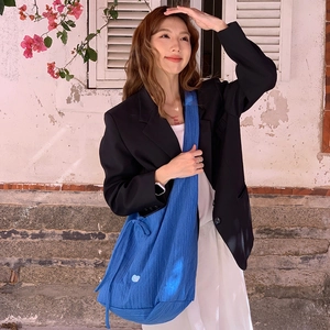 Royal blue hobo bag with vertical texture and round detail shown on a model
