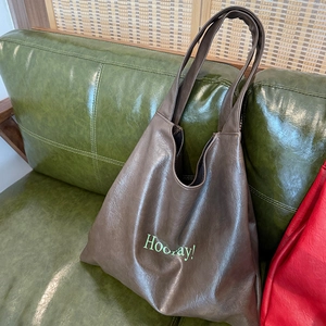 Detail of soft leather dark brown tote bag featuring green Hooray! lettering print