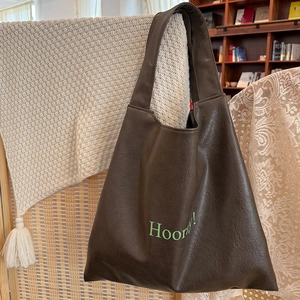 Detail view of brown faux leather tote bag with Hooray text in a cozy home setting