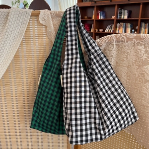 Detail shot of large vintage checkered tote bags in green and white hanging on wood