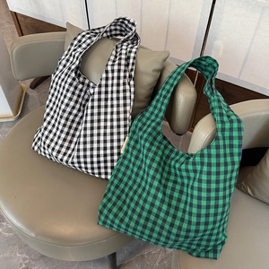 Detail of checkered canvas tote bags in black-white and green-black on a modern chair