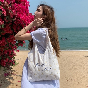 Borsa in tela floreale con scritta 'Gentle Soul' su sfondo di spiaggia assolata