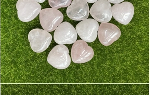 Macro di pietre di quarzo rosa a forma di cuore con texture naturali su uno sfondo verde