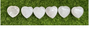 Pietre a cuore in quarzo rosa naturale lucido disposte su una trama di erba verde