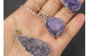 Close-up of raw amethyst cluster pendants with silver plated edges on a metal chain