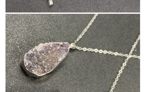 Close-up of raw purple amethyst crystal cluster pendant with silver-plated metallic edges