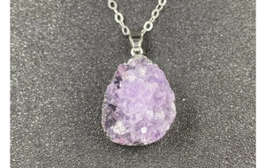 Macro shot of natural amethyst druzy pendant with silver electroplated edge detail