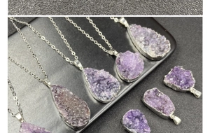 Detailed view of raw purple amethyst druzy pendants with silver plated edges on chains