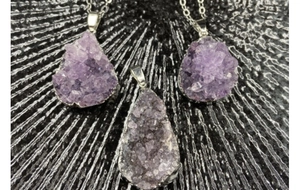 Detailed view of raw purple amethyst crystal cluster pendants with silver plated edges