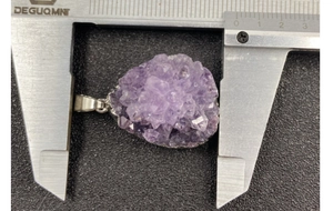 Macro shot of a drop-shaped amethyst cluster pendant measured with a digital caliper