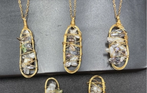 Dettaglio pendente fatto a mano in filo dorato con perle barocche e pietre miste