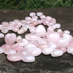 Pietre di quarzo rosa naturale a forma di cuore e ciottoli su sfondo di roccia scura
