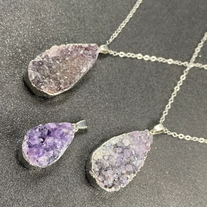 Natural amethyst druzy cluster pendant necklace with silver plated edge on dark background