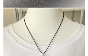 Detail of a black cord necklace with a silver metal clasp shown on a white mannequin