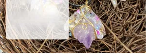 Macro detail of raw amethyst crystal cluster pendant wrapped in golden metal wire decoration
