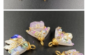 Macro detail of handmade wire-wrapped amethyst and crystal druzy pendants on black background