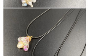 Detail of handmade amethyst wire wrapped pendant with irregular pearl on black cord