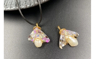 Detailed wire-wrapped amethyst and baroque pearl pendant on grey stone background