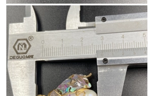Detail view of handmade wire-wrapped pearl pendant showing 2.3cm length on a caliper