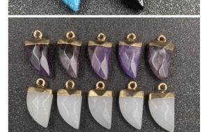 Dettaglio di ciondoli in ametista a forma di corno viola e bianco con bordi dorati