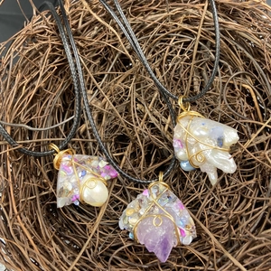 Handmade amethyst and pearl wire wrapped pendants on woven cords over a rustic twig background