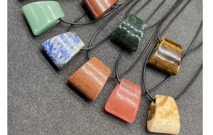 Collection of polished natural agate trapezoid pendants in various colors with black cords