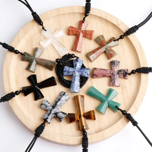 Ten pieces of natural gemstone cross necklaces in assorted stones on a wooden tray