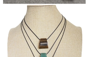 Tiger eye and green agate trapezoid pendants on black cords displayed on a neck bust