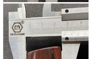 Measuring the 25mm width of a fan-shaped red agate pendant using a digital caliper