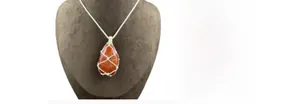 Macro detail of hand-knitted white net pouch holding a raw orange agate stone pendant