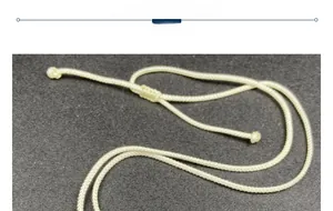 Close-up of cream woven necklace cord with adjustable knot on dark textured surface