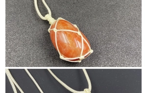 Macro detail of hand-woven net holding a polished red agate raw stone pendant