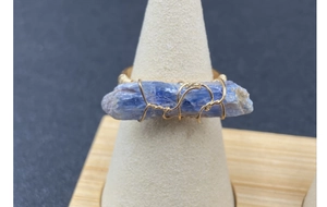 Dettaglio macro di anello fatto a mano in filo dorato con cianite blu naturale