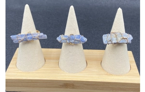 Tre anelli di cianite blu grezza avvolti in filo d'oro su supporti a forma di cono