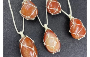 Close-up of four handmade net pocket necklaces with teardrop red agate stones
