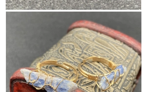 Dettaglio di anelli in cianite fatti a mano con filo dorato su scatola con texture vintage